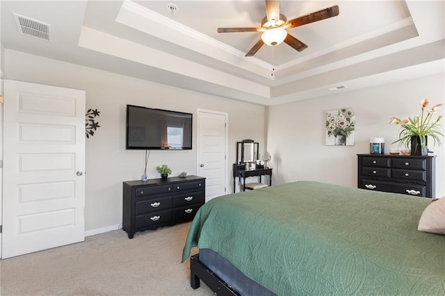 carpeted bedroom with a tray ceiling and ceiling fan