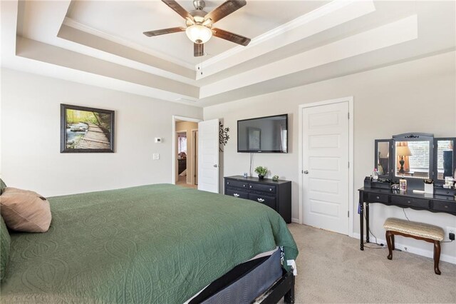 carpeted bedroom featuring a raised ceiling and ceiling fan