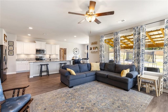 living room featuring ceiling fan, dark hardwood / wood-style flooring, plenty of natural light, and sink