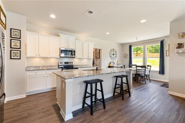 kitchen featuring white cabinetry, a kitchen island with sink, dark hardwood / wood-style flooring, and appliances with stainless steel finishes