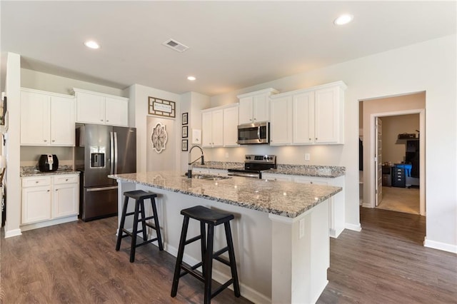 kitchen with appliances with stainless steel finishes, white cabinetry, a kitchen island with sink, and sink