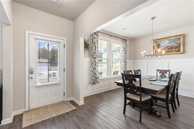 dining space featuring a wealth of natural light, dark wood-type flooring, and a notable chandelier