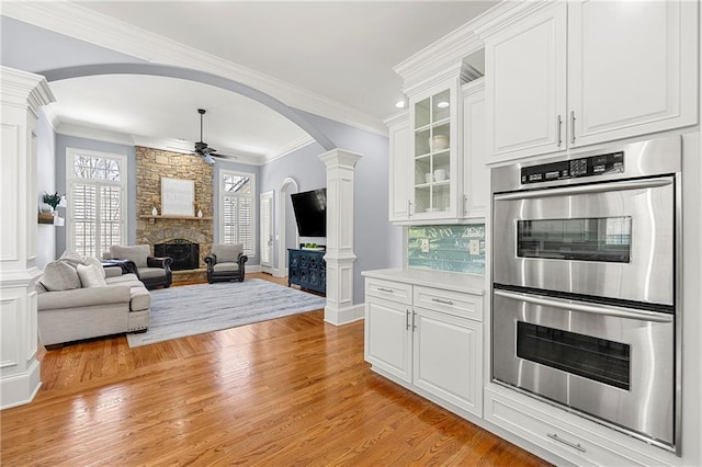 4080 Glen Hill Way NE, Marietta, GA 30066 - kitchen with stainless steel double oven, arched walkways, a stone fireplace, ornate columns, and light wood-style floors