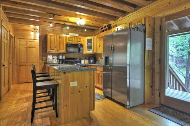 kitchen with light wood-style flooring, black microwave, stainless steel fridge with ice dispenser, beamed ceiling, and electric range