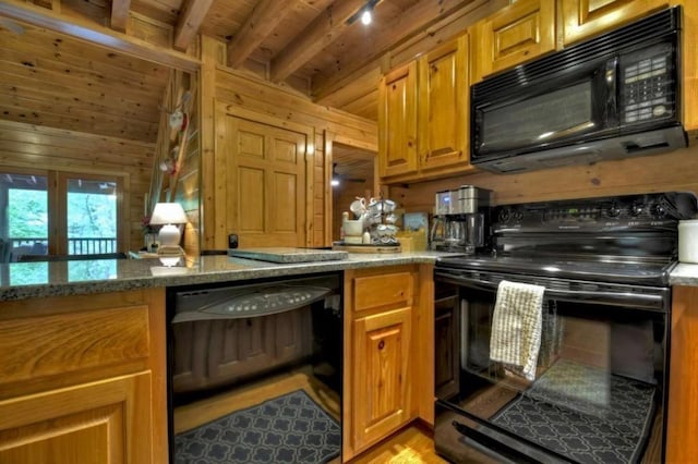 kitchen with brown cabinets, beamed ceiling, black appliances, wooden walls, and light stone counters