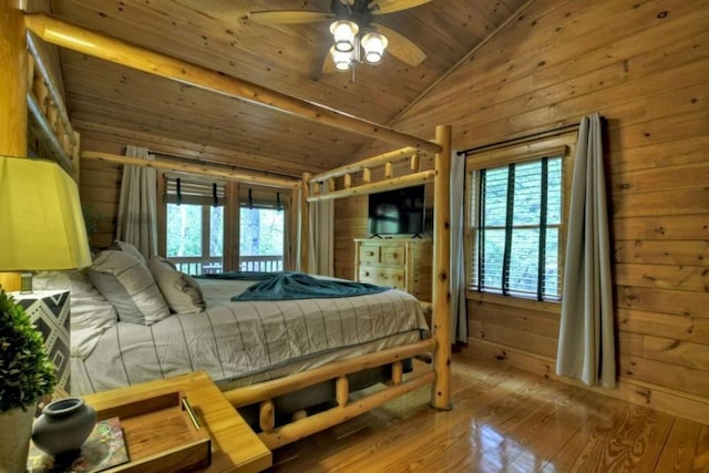 bedroom featuring lofted ceiling, multiple windows, wooden walls, and hardwood / wood-style floors