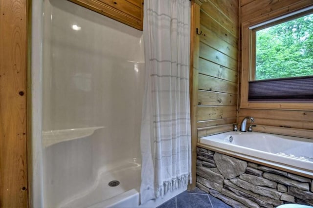 full bathroom with tile patterned flooring, wooden walls, a garden tub, and a shower stall