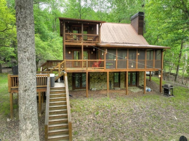back of property featuring a chimney, metal roof, stairs, a sunroom, and a deck
