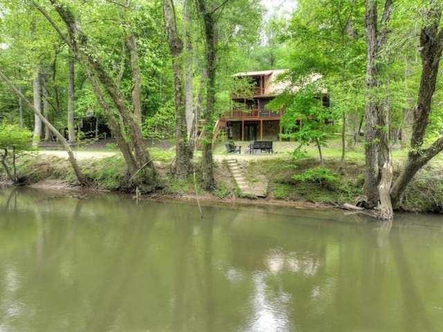 water view featuring stairway and a wooded view