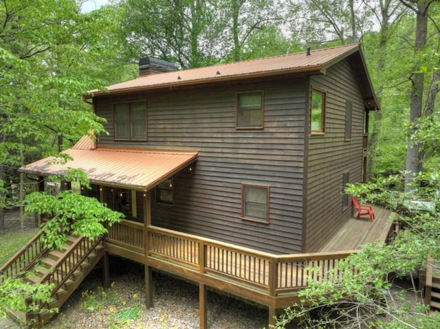 back of property featuring a chimney, metal roof, and a deck
