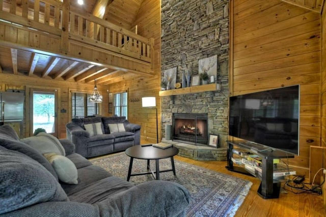 living area with a fireplace, wooden walls, beam ceiling, and wood finished floors