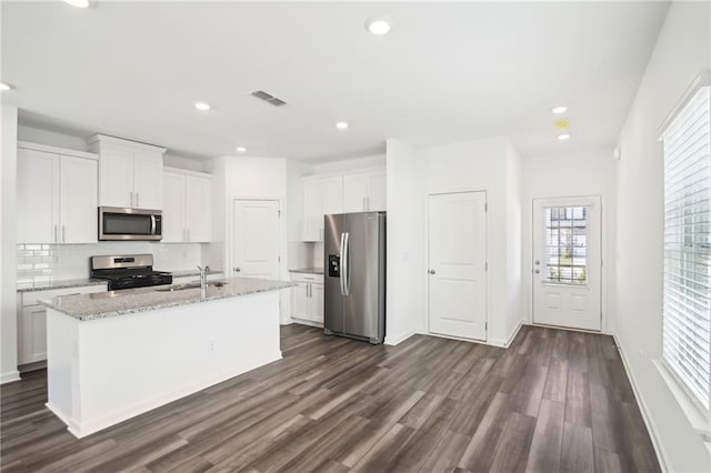 kitchen featuring sink, appliances with stainless steel finishes, light stone counters, an island with sink, and white cabinets