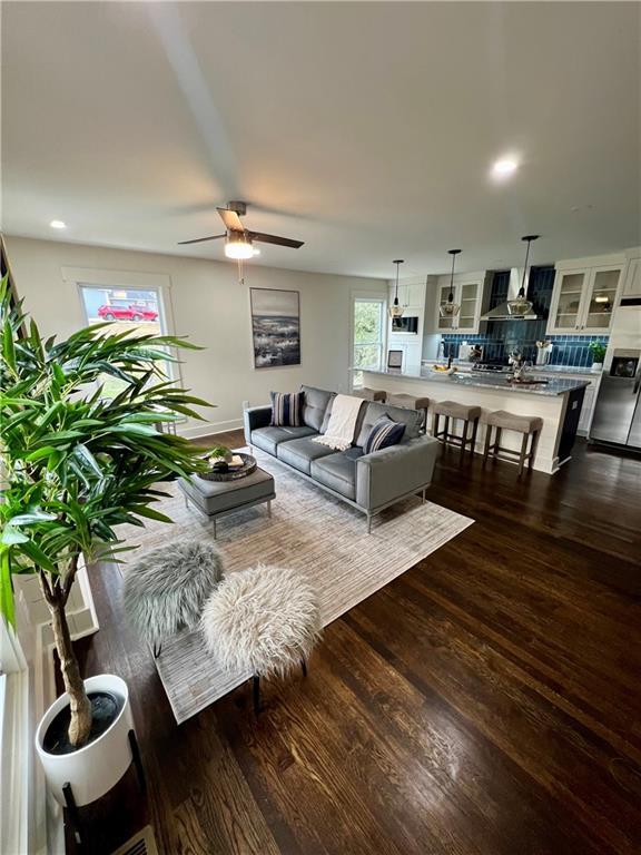 living room with ceiling fan, a healthy amount of sunlight, and dark wood-type flooring