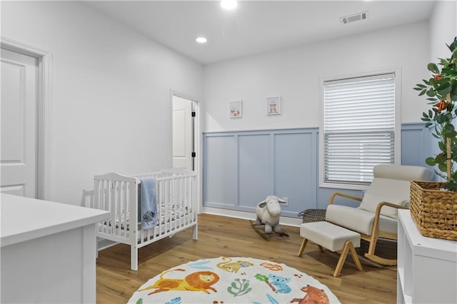 2013 White Cypress Ct, Smyrna, GA 30082 - bedroom featuring a nursery area, a wainscoted wall, light wood-style flooring, a decorative wall, and recessed lighting