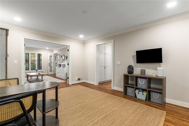 living room featuring wood finished floors, ornamental molding, baseboards, and recessed lighting
