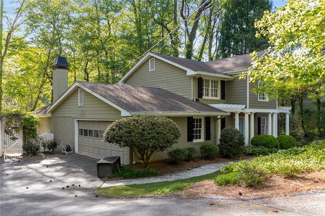 view of front of house with a garage, driveway, a chimney, and brick siding
