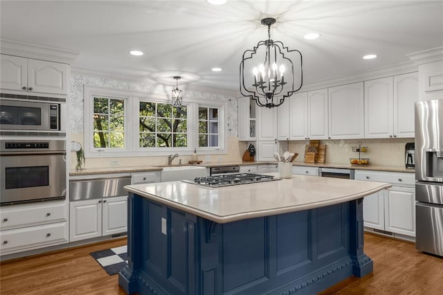 kitchen featuring appliances with stainless steel finishes, a warming drawer, a sink, white cabinets, and recessed lighting