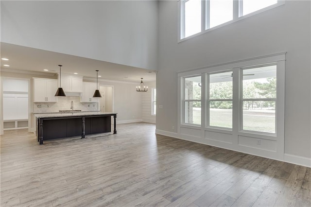 living room featuring hardwood / wood-style flooring, ornamental molding, sink, and ceiling fan with notable chandelier