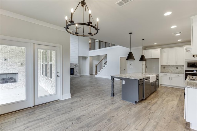 kitchen featuring an island with sink, decorative light fixtures, sink, white cabinets, and decorative backsplash