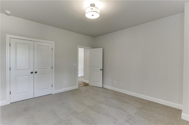 unfurnished bedroom with a closet and light colored carpet