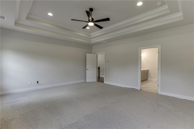 unfurnished bedroom with light carpet, crown molding, ensuite bath, and a raised ceiling