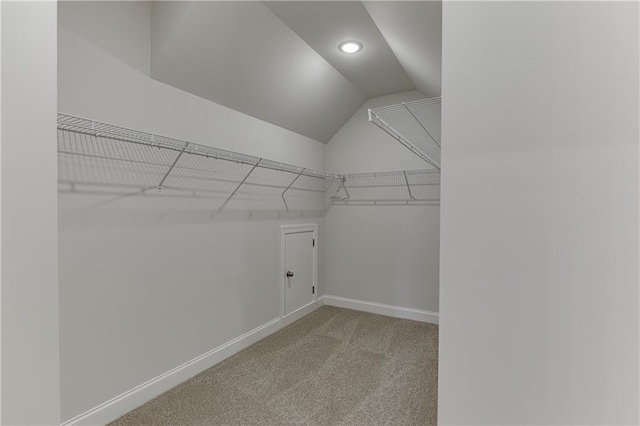 walk in closet with light carpet and lofted ceiling