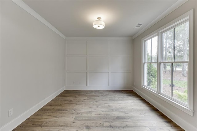 spare room featuring ornamental molding and light wood-type flooring