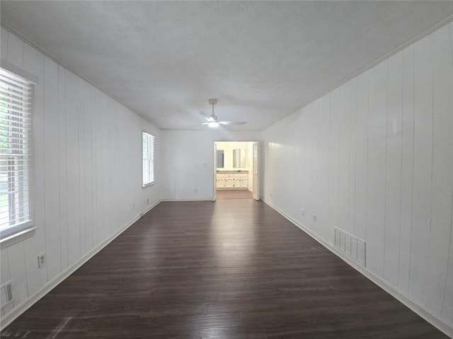 2821 NE Meadowlark Trl, Duluth, GA 30096 - empty room with dark wood-style floors, ceiling fan, baseboards, wooden walls, and crown molding