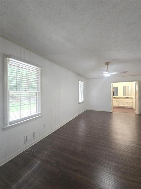 2821 NE Meadowlark Trl, Duluth, GA 30096 - unfurnished living room featuring dark wood-style flooring, a ceiling fan, baseboards, and a textured ceiling