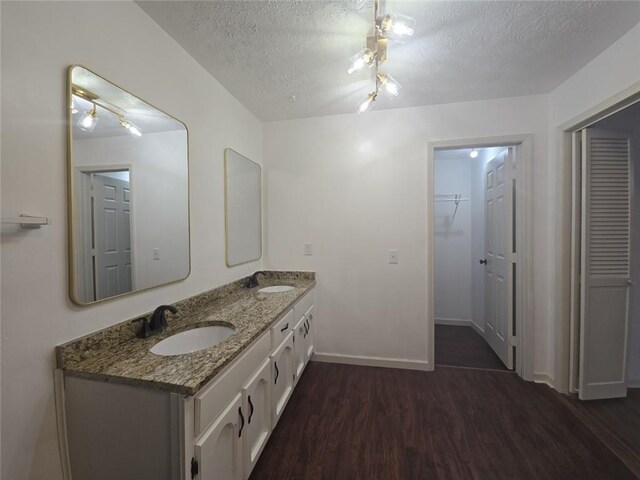 2821 NE Meadowlark Trl, Duluth, GA 30096 - bathroom featuring a textured ceiling, wood finished floors, a closet, double vanity, and baseboards