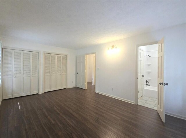 2821 NE Meadowlark Trl, Duluth, GA 30096 - unfurnished bedroom with wood finished floors, baseboards, multiple closets, and ensuite bathroom