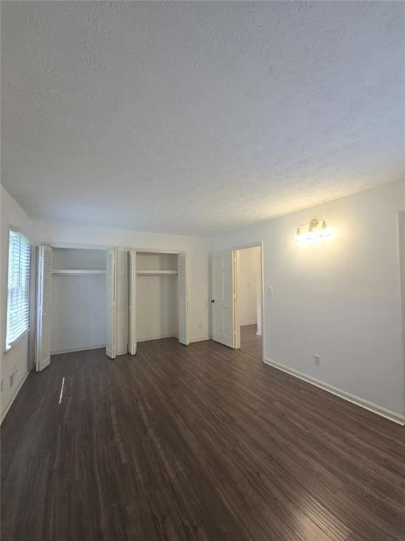2821 NE Meadowlark Trl, Duluth, GA 30096 - unfurnished bedroom featuring multiple closets, dark wood-style floors, baseboards, and a textured ceiling