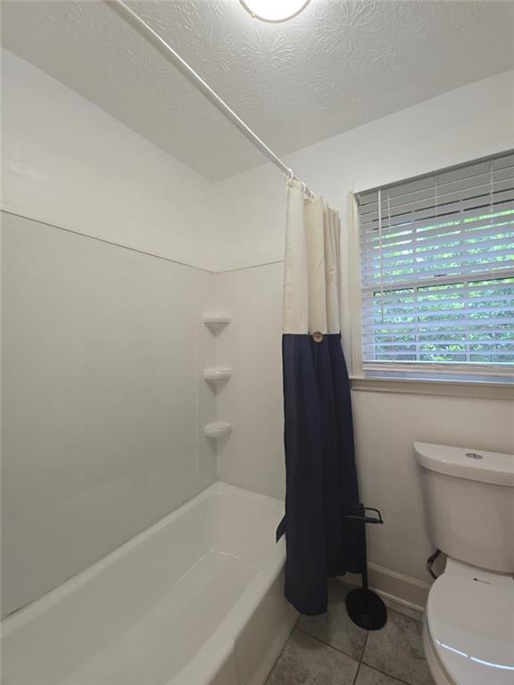 2821 NE Meadowlark Trl, Duluth, GA 30096 - full bath with toilet, shower / bath combo, tile patterned flooring, a textured ceiling, and baseboards