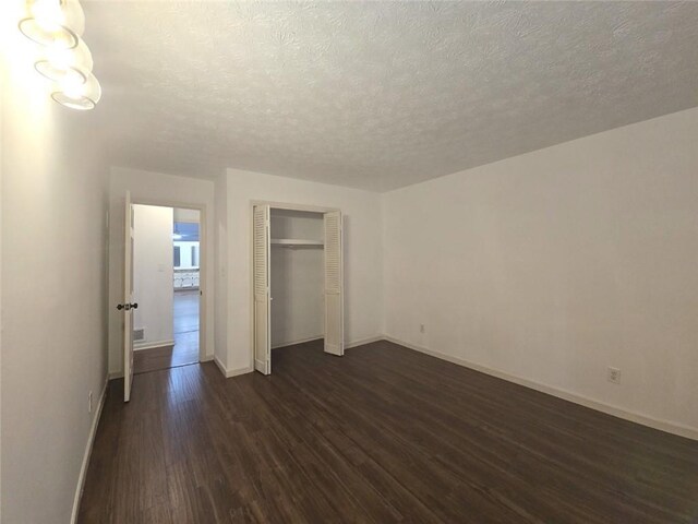 2821 NE Meadowlark Trl, Duluth, GA 30096 - unfurnished bedroom featuring dark wood-style floors, baseboards, a textured ceiling, and a closet