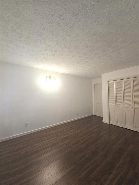 2821 NE Meadowlark Trl, Duluth, GA 30096 - unfurnished bedroom featuring a textured ceiling, dark wood-type flooring, baseboards, and a closet