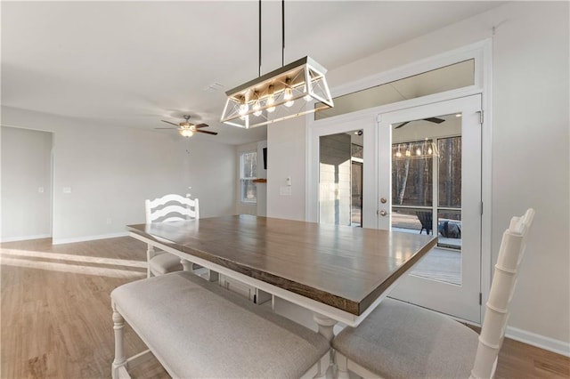 dining area with baseboards, french doors, a ceiling fan, and light wood-style flooring
