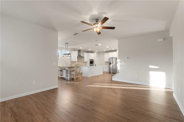 living room with wood finished floors, a ceiling fan, visible vents, baseboards, and recessed lighting