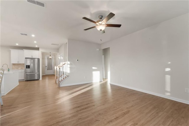 unfurnished living room featuring visible vents, baseboards, ceiling fan, and a sink