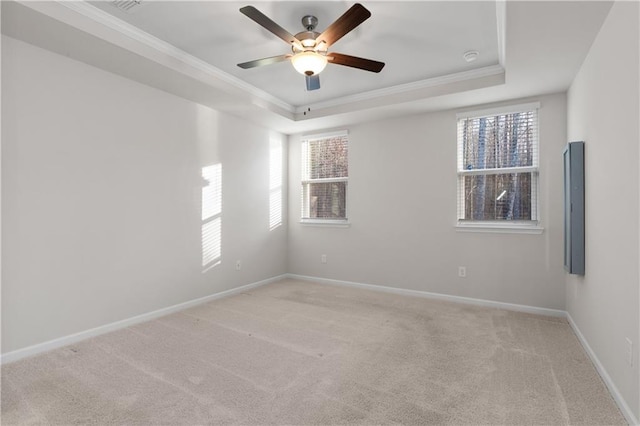 spare room with carpet flooring, a tray ceiling, crown molding, baseboards, and ceiling fan