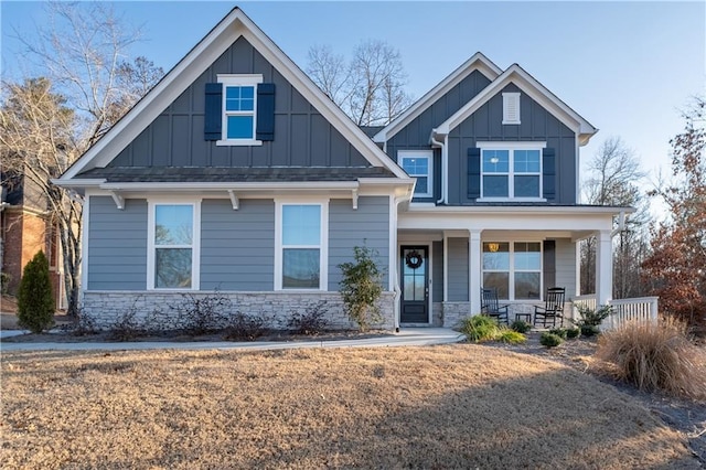 craftsman-style home with covered porch, stone siding, and board and batten siding