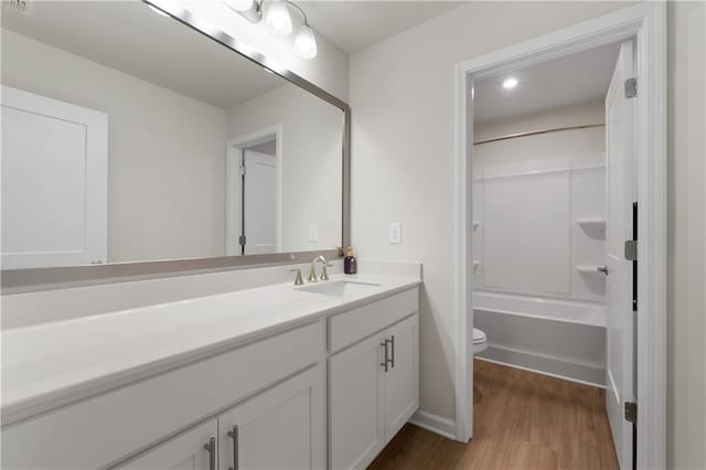 bathroom with vanity, toilet, shower / bathtub combination, and wood finished floors