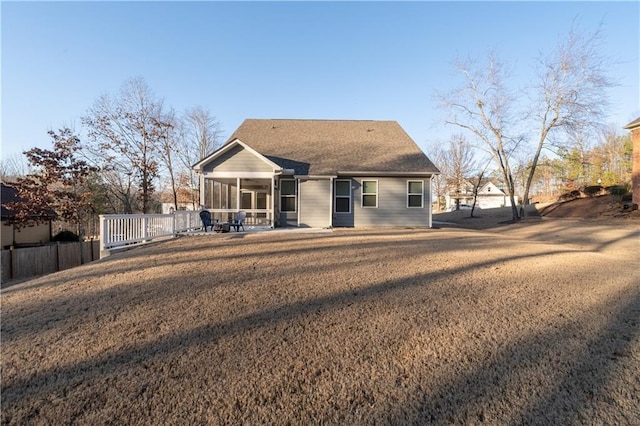 back of property with a yard, a sunroom, and a ceiling fan