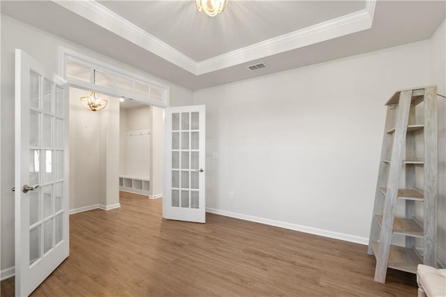 unfurnished room featuring wood finished floors, french doors, a notable chandelier, visible vents, and ornamental molding