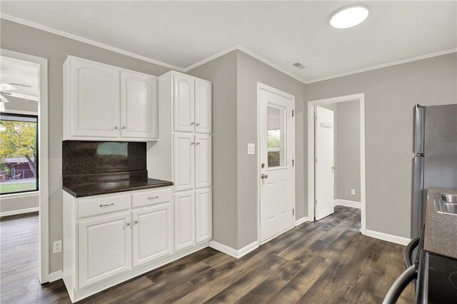 kitchen featuring white cabinetry, dark wood-type flooring, backsplash, stainless steel fridge, and ornamental molding