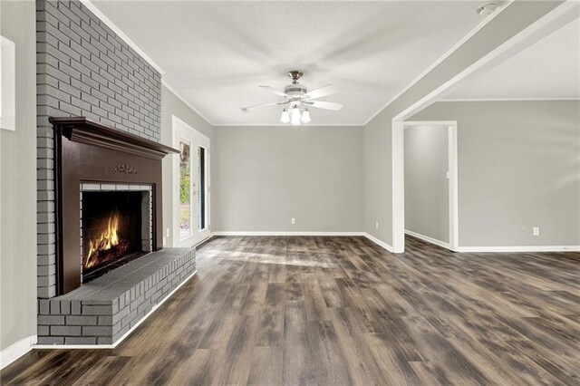 unfurnished living room with crown molding, ceiling fan, dark wood-type flooring, and a brick fireplace