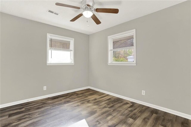 empty room with dark hardwood / wood-style flooring, ceiling fan, and plenty of natural light