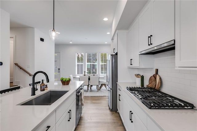 kitchen featuring white cabinets, appliances with stainless steel finishes, pendant lighting, and sink