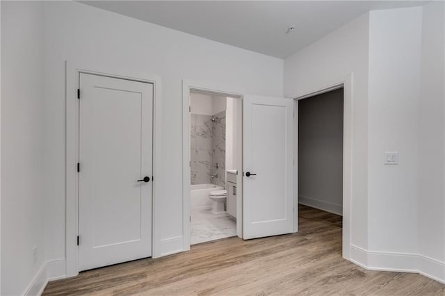 unfurnished bedroom with light hardwood / wood-style floors, ensuite bath, and a closet