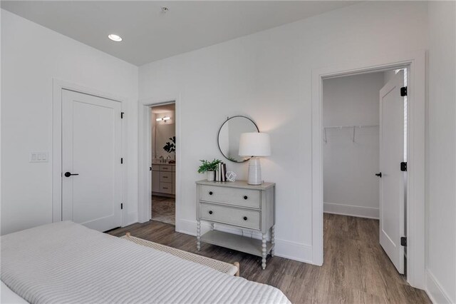 bedroom featuring a closet, ensuite bathroom, hardwood / wood-style floors, and a spacious closet