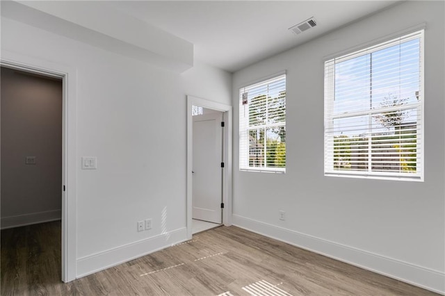 unfurnished bedroom featuring a spacious closet, a closet, and light wood-type flooring